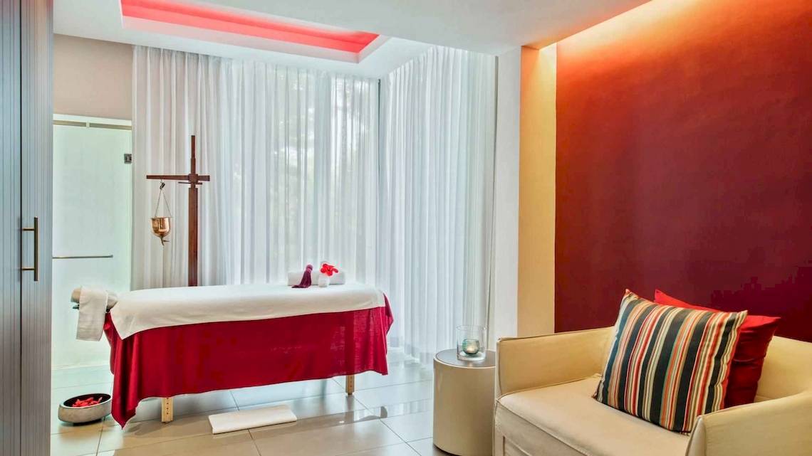 Massageraum im Long Beach Mauritius Hotel mit rotem Massagetisch und weißen Vorhängen.