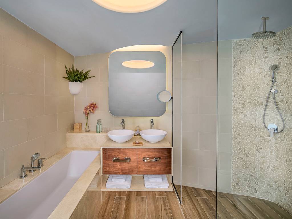 Das Badezimmer im Retreat Palm Dubai MGallery by Sofitel mit Badewanne, zwei Waschbecken und Dusche.