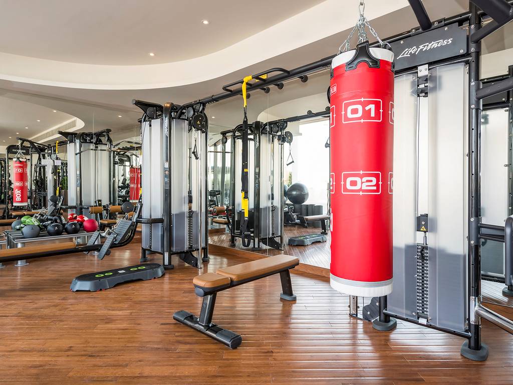 Fitnessstudio im Retreat Palm Dubai MGallery by Sofitel mit roten Boxsäcken und Trainingsgeräten