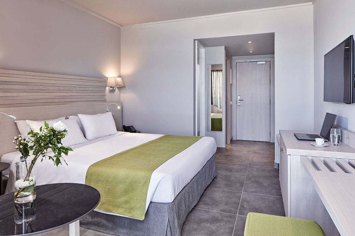 Hotelzimmer im Sentido Unique Blue Resort & Villas mit einem Bett, Tisch, Fernseher und Schreibtisch.