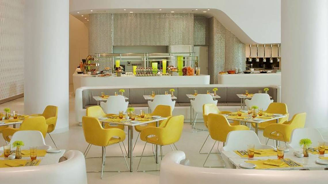 Restaurant im W Abu Dhabi Hotel auf Yas Island mit gelben und weißen Stühlen und Tischen.