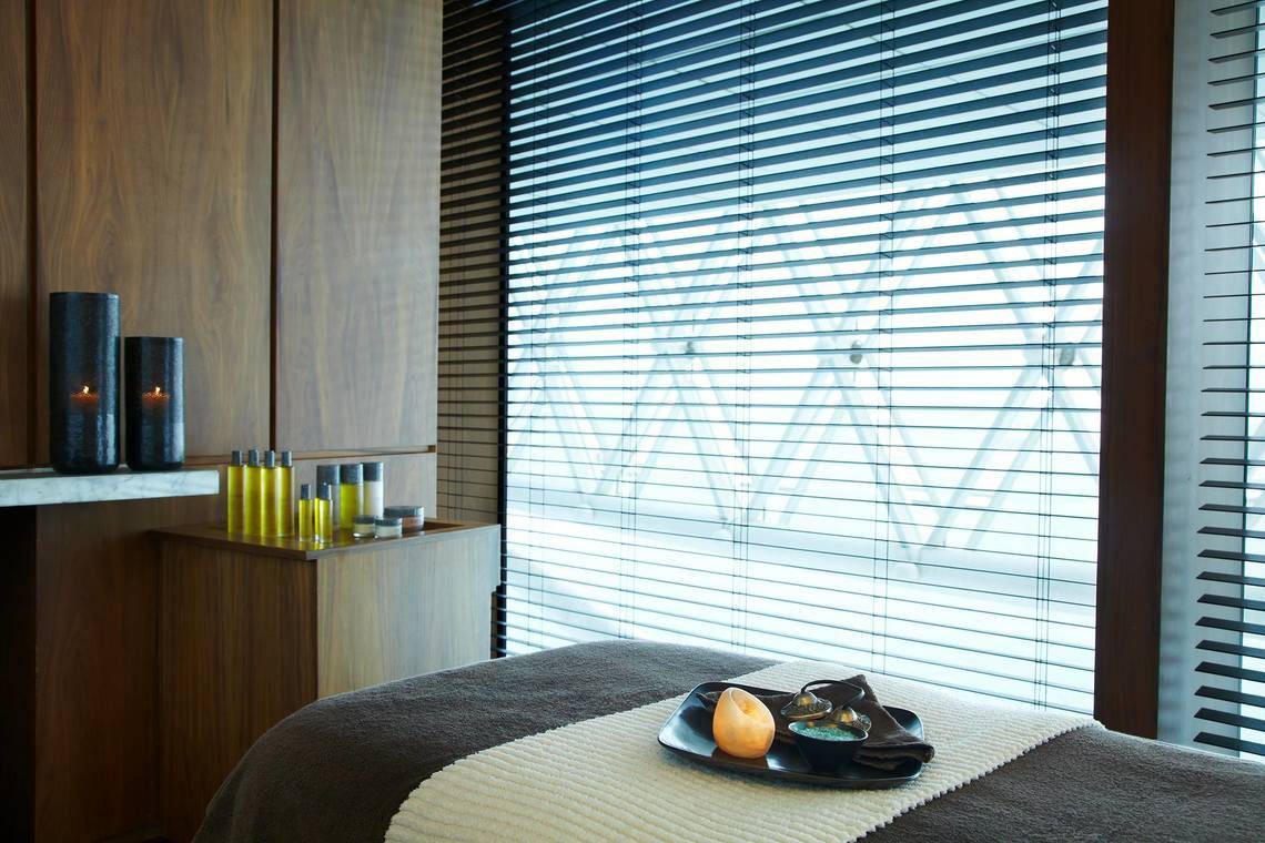 Behandlungsraum im W Abu Dhabi - Yas Island mit Massageliege, Kerzen und Produkten.