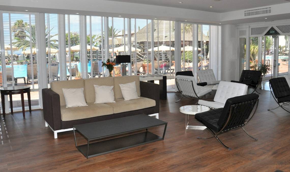 Lobby des H10 Timanfaya Palace mit Sofas, Tischen und Blick auf den Pool.