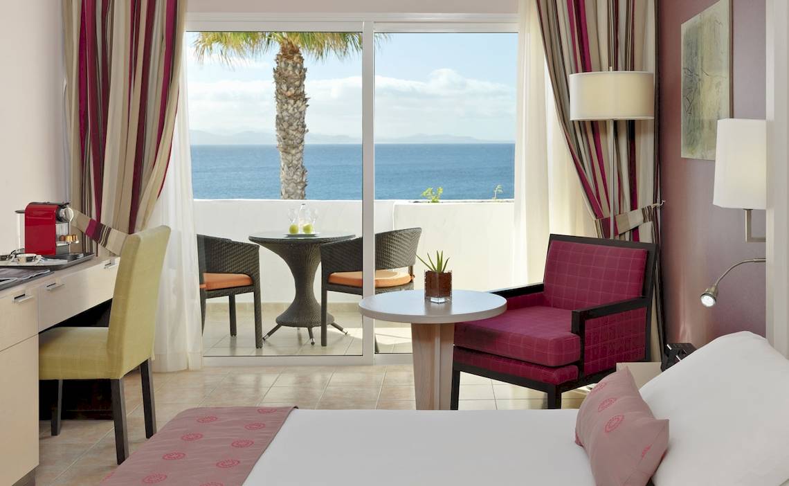 Zimmer im H10 Timanfaya Palace Hotel mit Blick auf das Meer und eine Terrasse.