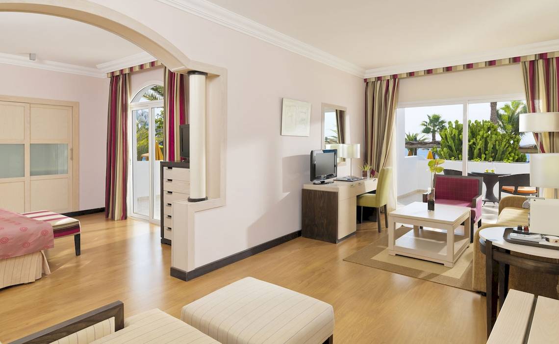 Innenansicht einer Suite im H10 Timanfaya Palace mit Wohnzimmer, Schlafzimmer und Schreibtisch.