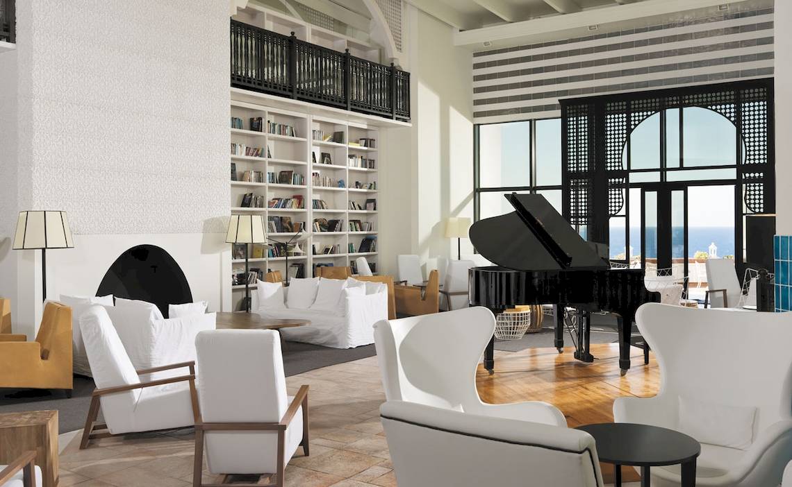 Lobby des H10 Timanfaya Palace mit weißen Sofas, einem Klavier und Blick auf das Meer.