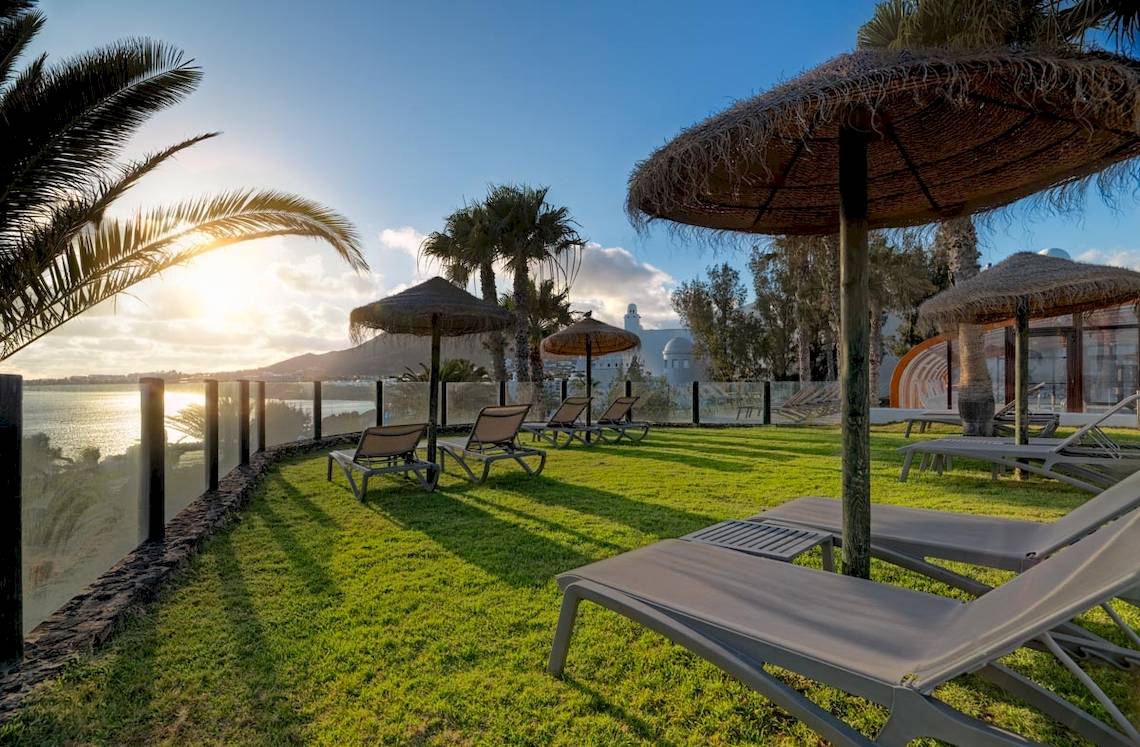 Terrasse des H10 Timanfaya Palace mit Liegen und Sonnenschirmen am Meer