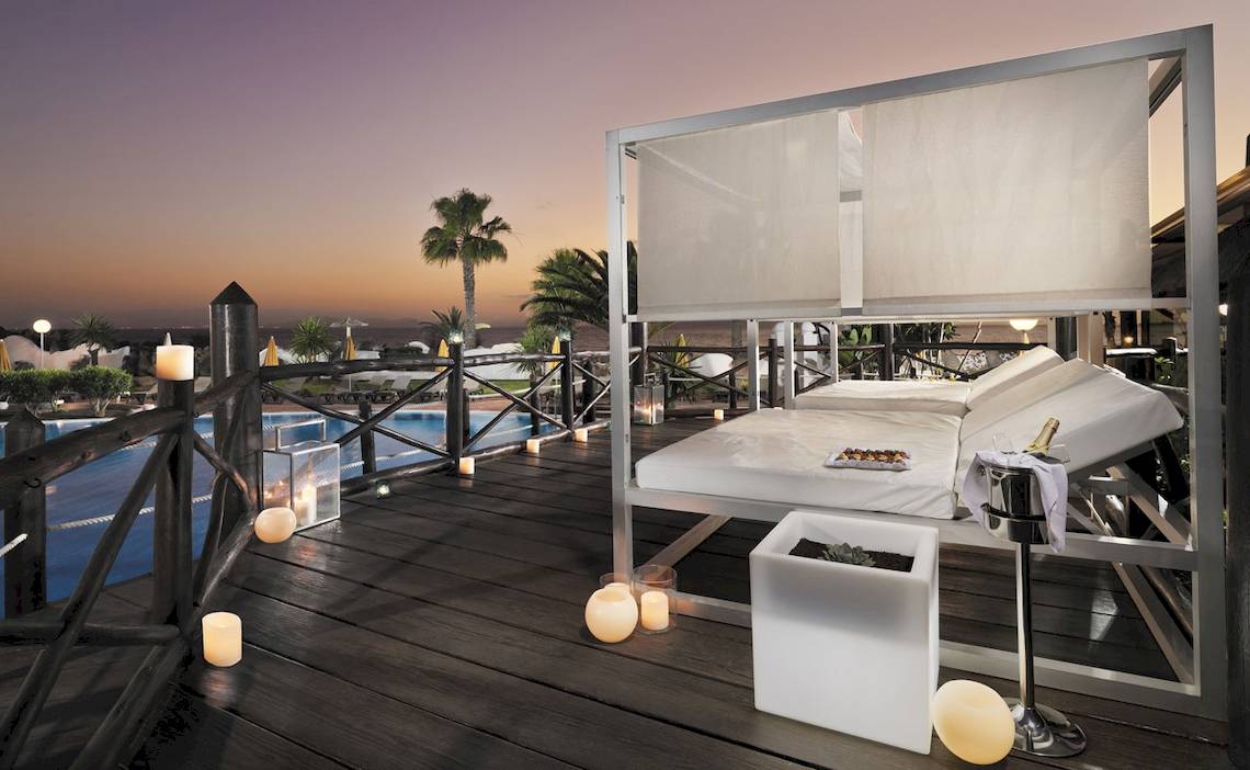 Terrasse des H10 Timanfaya Palace mit Loungebett, Pool und Kerzen bei Nacht