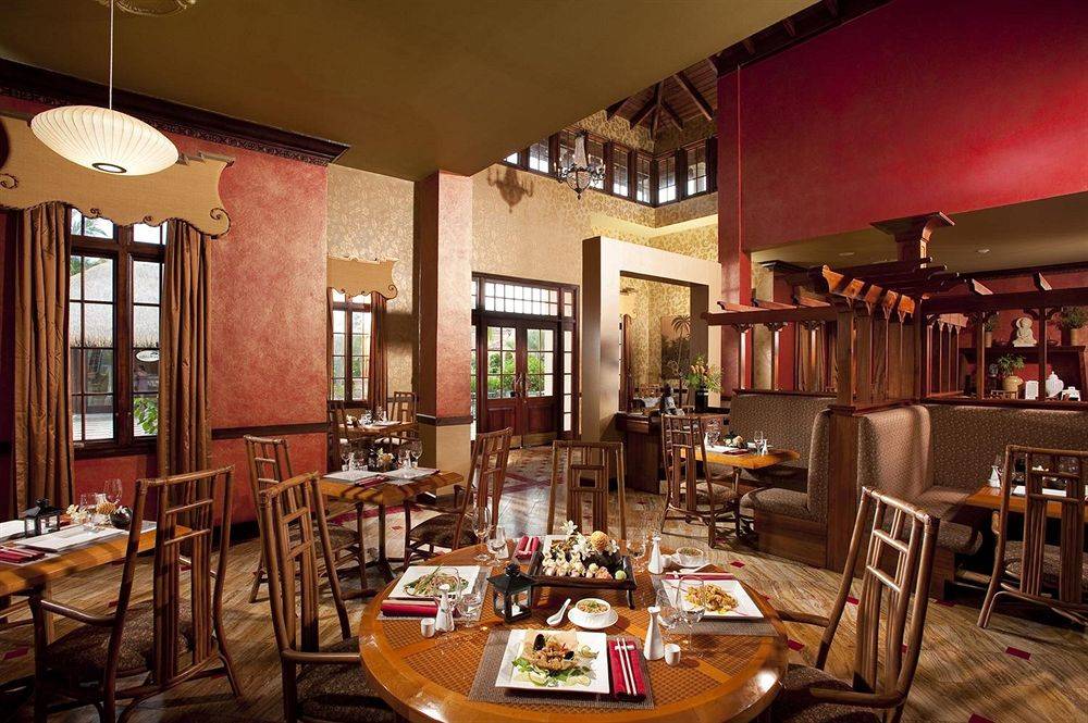 Innenansicht des Restaurants im Sandals Whitehouse European Village & Spa mit runden Tischen und Speisen.