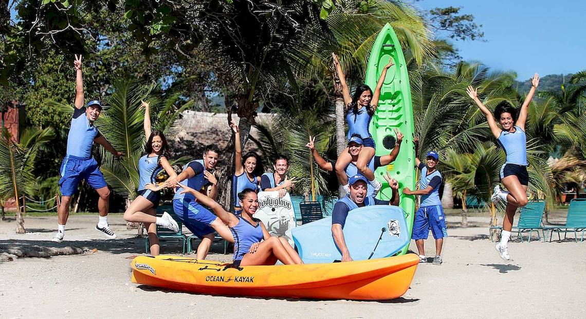 Gruppe von Mitarbeitern des Barcelo Tambor Hotels posiert mit Kajaks am Strand.