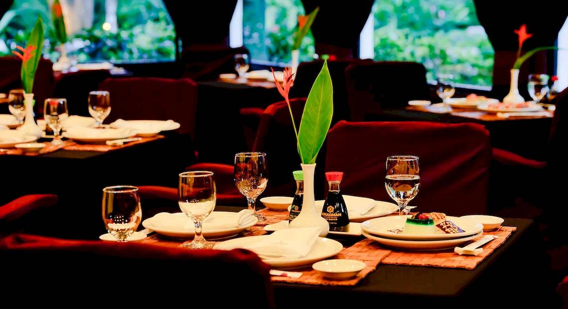 Restauranttisch im Barcelo Tambor Hotel mit Geschirr, Gläsern und Pflanzendekor.