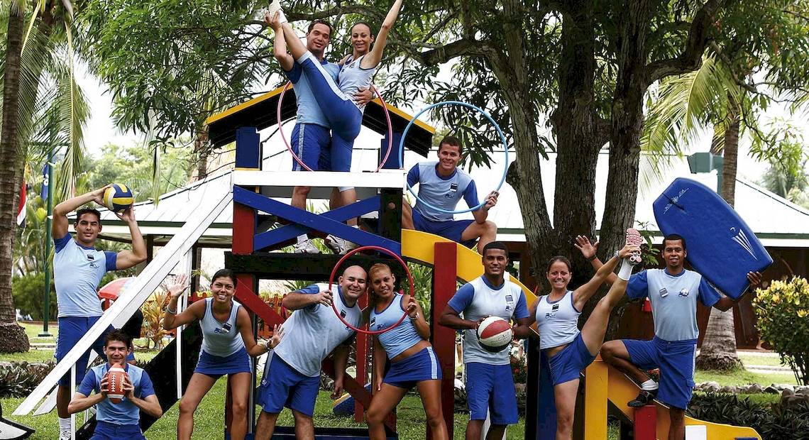 Gruppe junger Athleten des Barcelo Tambor Hotels beim Sport vor einem Spielplatz