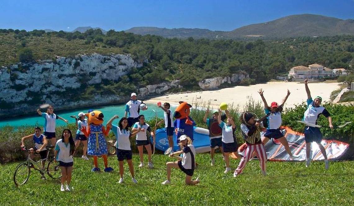 Gruppe von Mitarbeitern des Blau Punta Reina Hotels auf einem Rasenfeld neben dem Strand.