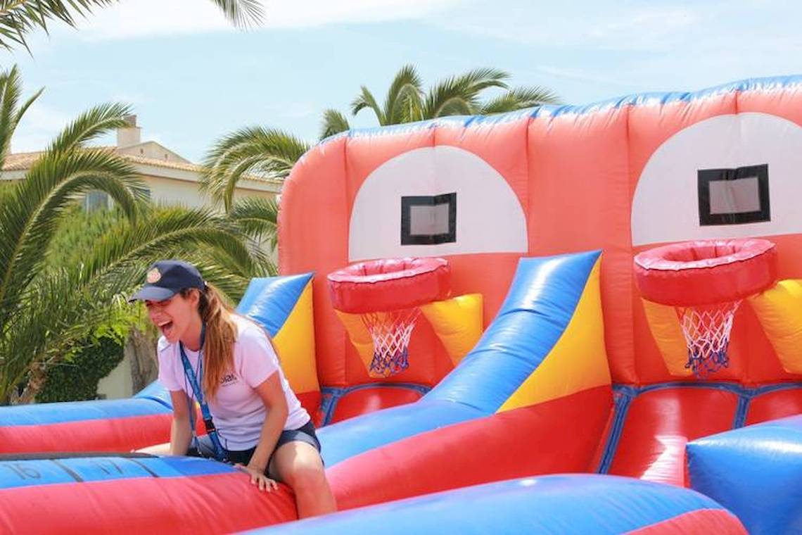 Frau auf einer aufblasbaren Basketball-Rutsche im Blau Punta Reina Hotel