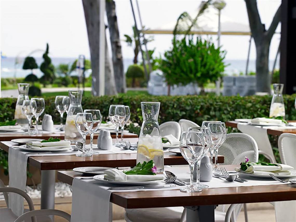 Gartentisch des Atlantica Miramare Beach Hotels, gedeckt mit Geschirr und Gläsern.