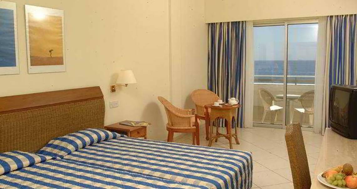 Doppelzimmer im Atlantica Miramare Beach Hotel mit Meerblick, Bett, Tisch, Fernseher und Balkon.