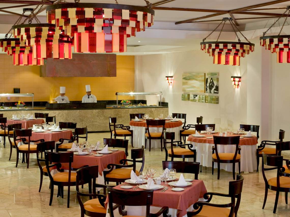 Restaurant im Grand Sunset Princess All Suites Resort mit orange Tischdecken und roten Kronleuchtern.