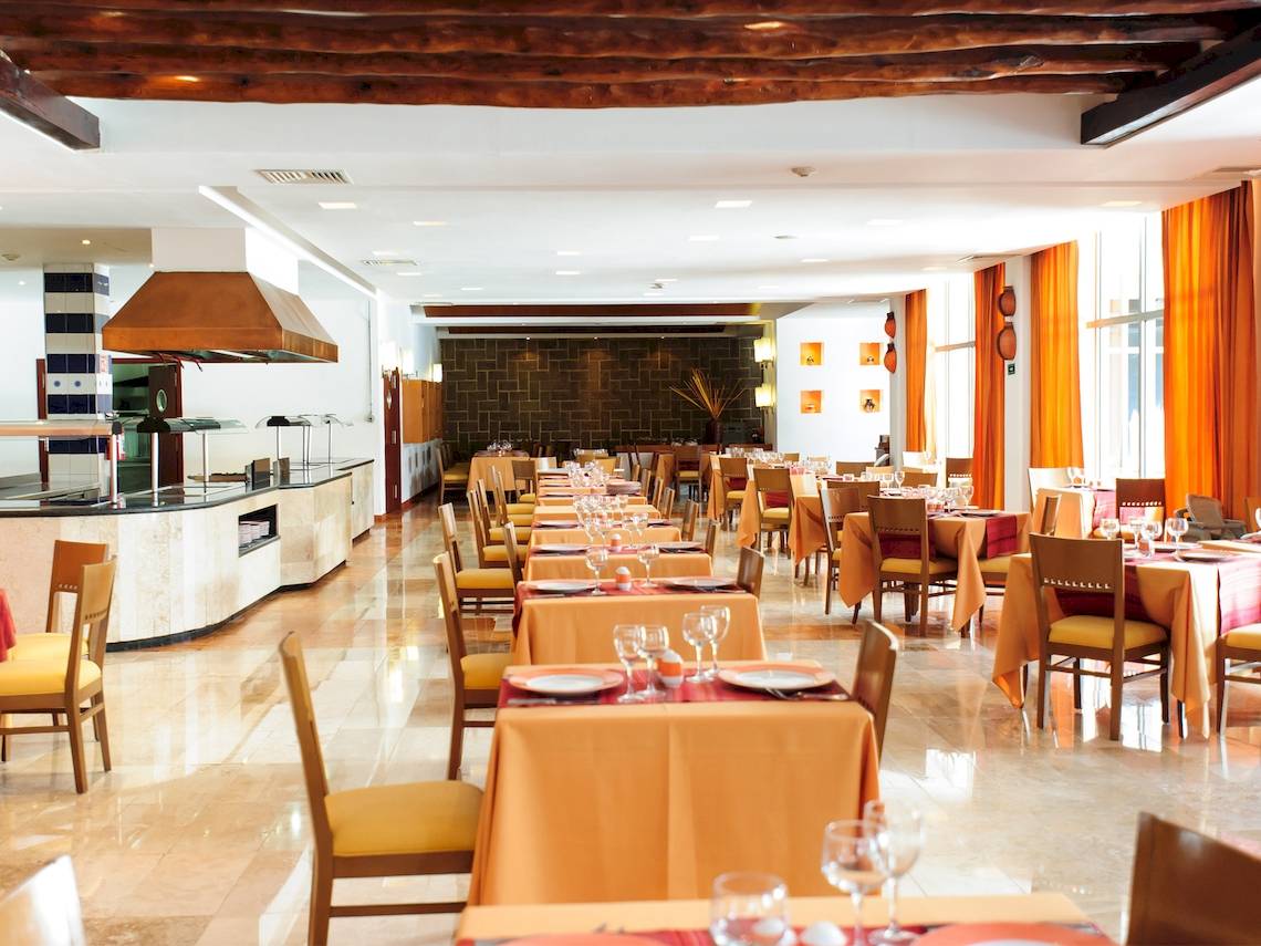 Innenansicht des Restaurants im Grand Sunset Princess All Suites Resort mit gedeckten Tischen und Stühlen.
