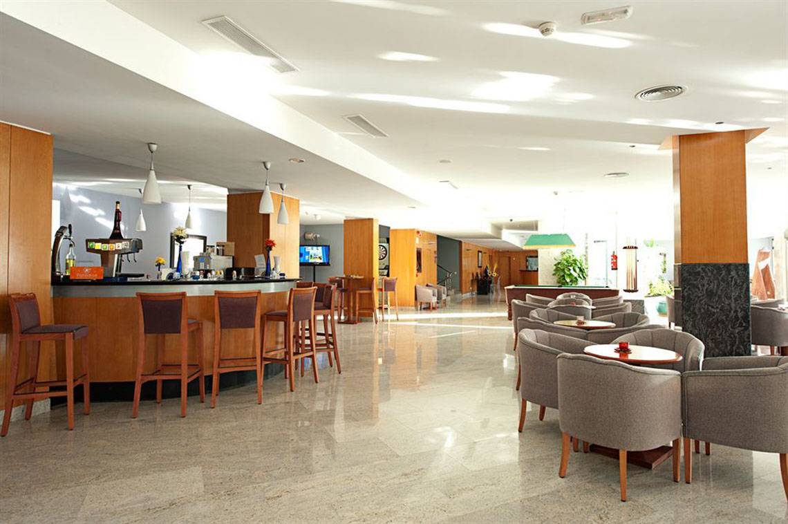 Barbereich im LIVVO Costa Taurito Hotel mit Holzstühlen und Tischen.