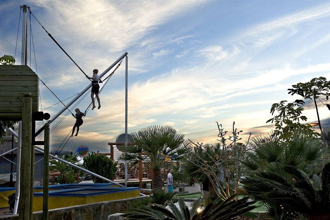 Zwei Personen auf Bungee-Seilschwingen im LIVVO Costa Taurito Hotel bei Sonnenuntergang.