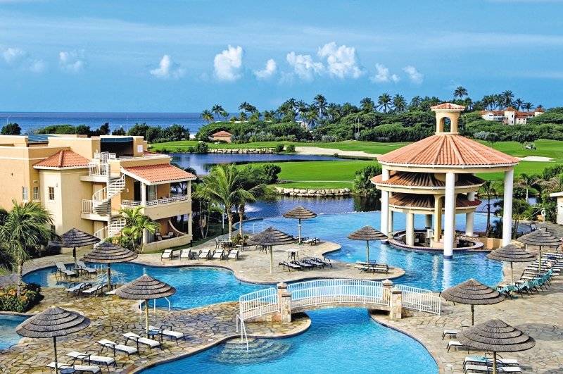 Ein Resort mit einem großen Pool, einem Pavillon und Sonnenliegen am Divi Tamarijn Aruba und Divi Village.