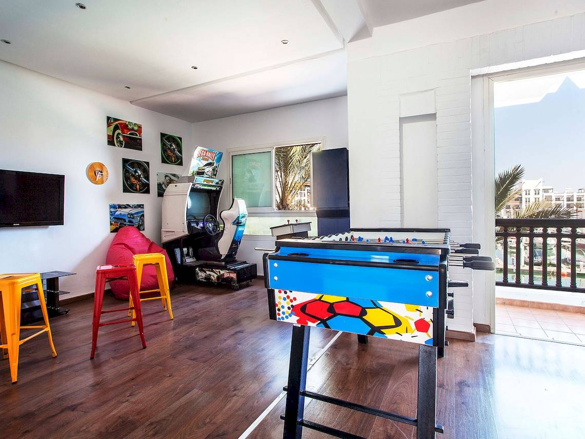 Spielzimmer im Bianca Beach Resort mit Fernseher, Spielkonsole, Tischfußball und bunten Stühlen.