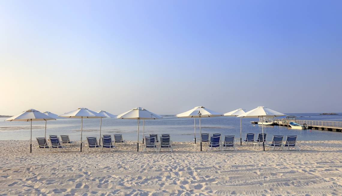Strand des Wyndham Garden Salalah Mirbat mit Liegen und Umbrellas am Meer