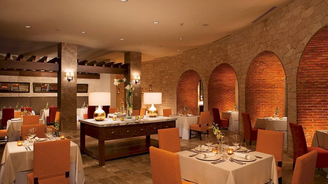Innenbereich des Restaurants im Secrets Akumal Riviera Maya mit runden Bögen und Steinwänden.