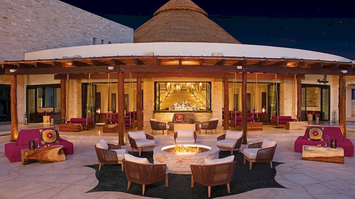 Hotellounge bei Nacht des Secrets Akumal Riviera Maya mit einem zentralen Feuerplatz und umliegenden Möbeln.
