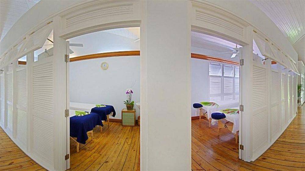 Massage-Behandlungsraum im Couples Negril Hotel mit zwei Massagetischen und einem Pflanzentopf.