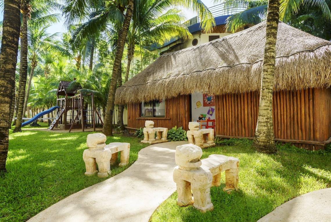 Kinderbereich im The Reef Coco Beach Hotel mit Spielhaus, Rutsche und hügeligen Pfaden.