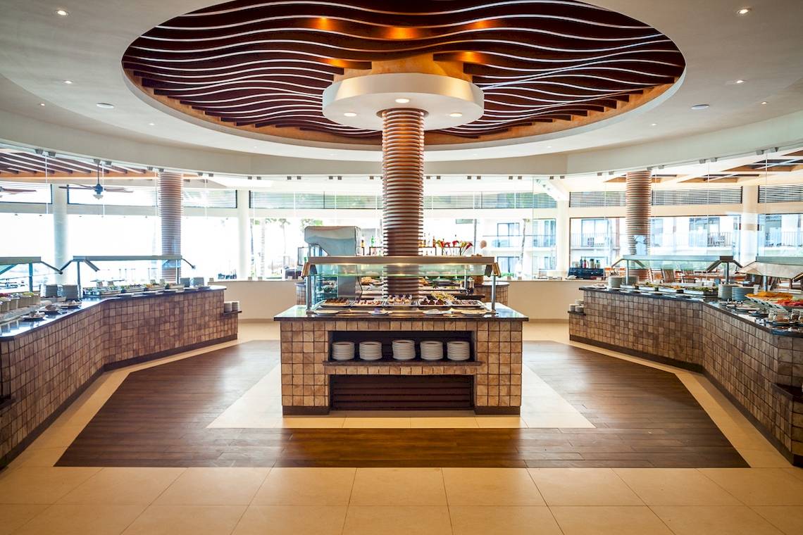 Buffetbereich im Reef Coco Beach Hotel mit vielen Gerichten und modernen Holzböden.