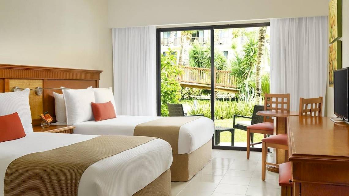 Zwei Betten in einem Hotelzimmer mit Blick auf eine Terrasse und einen Garten