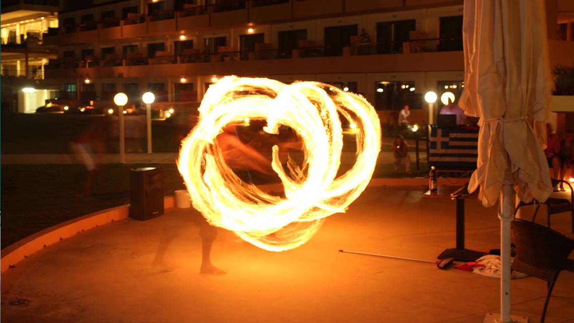 Eine Feuershow vor dem Kiani Beach Resort Hotel bei Nacht mit einem Performer und brennenden Seilen.