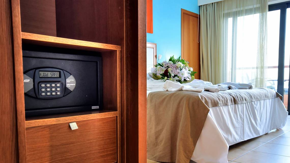 Ein Hotelzimmer mit einem Safe im Schrank und einem Bett mit Blumen.