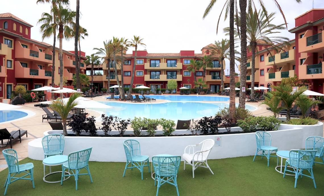 Außenpoolbereich des Bluesea Aloe Corralejo Hotels mit blauen Liegestühlen und weißen Sonnenschirmen.