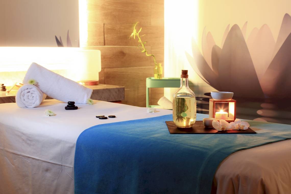 Spa-Behandlungsraum im Bluesea Aloe Corralejo Hotel mit Massagetisch, Kerzen und Ölflasche.