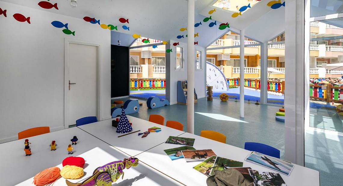 Ein farbenfrohes Kinderzimmer im Aparthotel Allegro Isora mit Spielzeug und Wanddekoration.