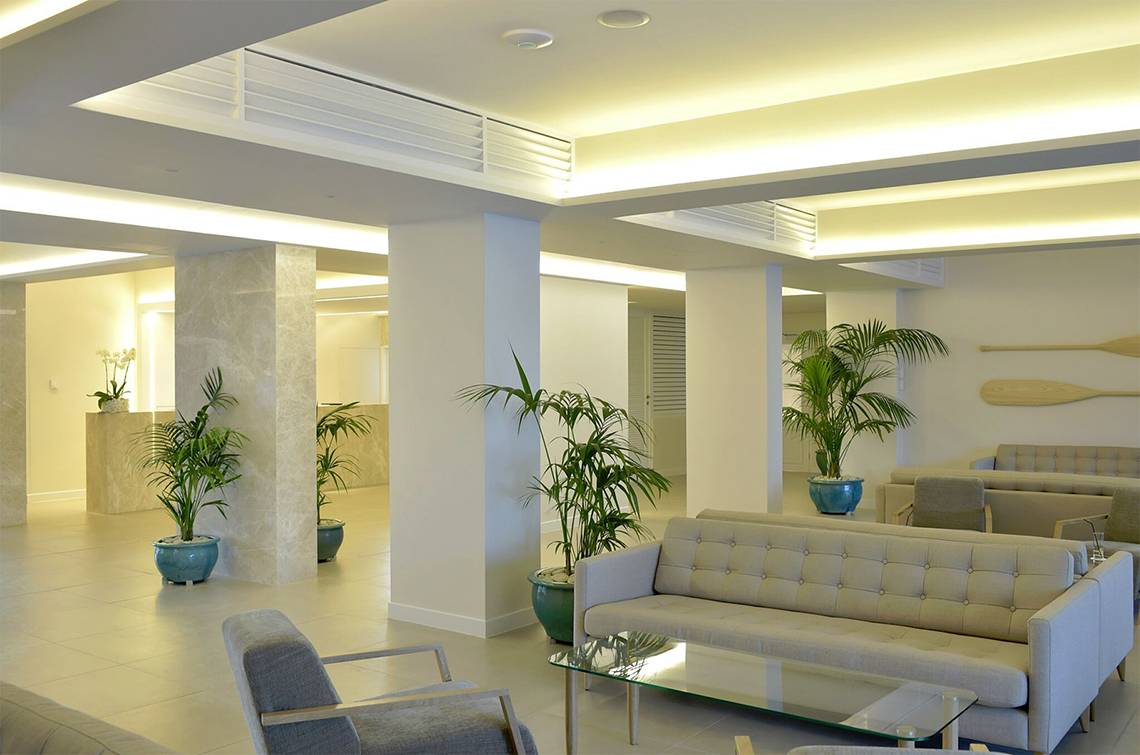Lobby-Bereich des Sunrise Gardens Hotels mit gepolsterten Sofas, Tischen und Pflanzen in blauen Töpfen.