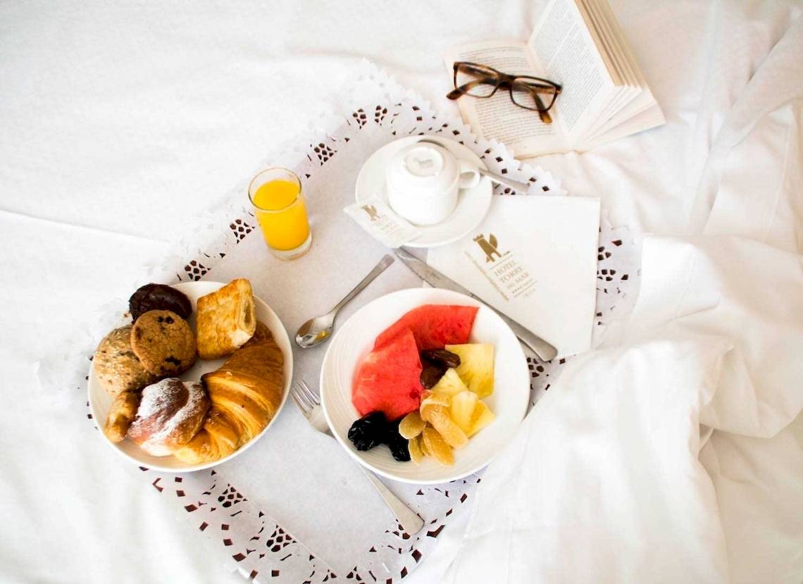 Frühstücksbuffet im Torre del Mar Hotel mit Croissants, Früchten und einem Glas Orangensaft.