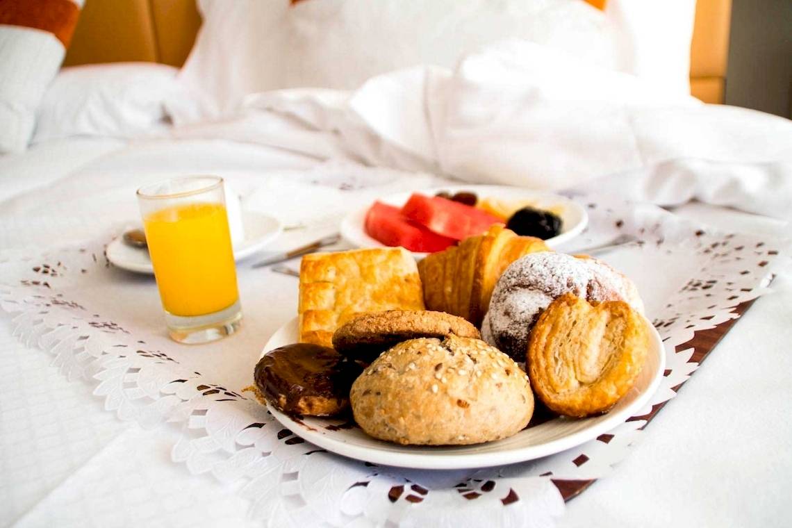 Frühstücksbuffet im Torre del Mar Hotel mit verschiedenen Gebäck, Früchten und einem Glas Orangensaft.