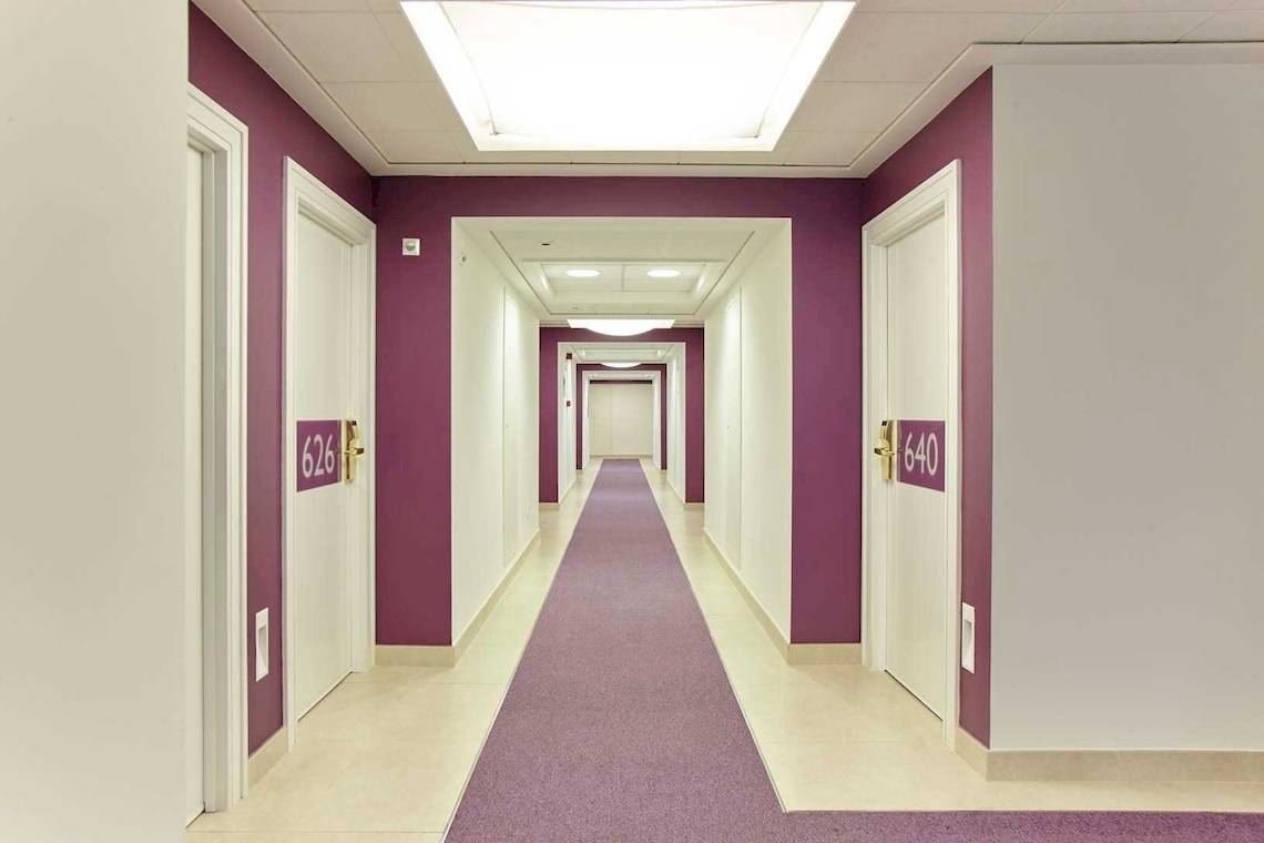 Eingangsflur des Hotels Torre del Mar mit lila Wänden und weißen Türen.