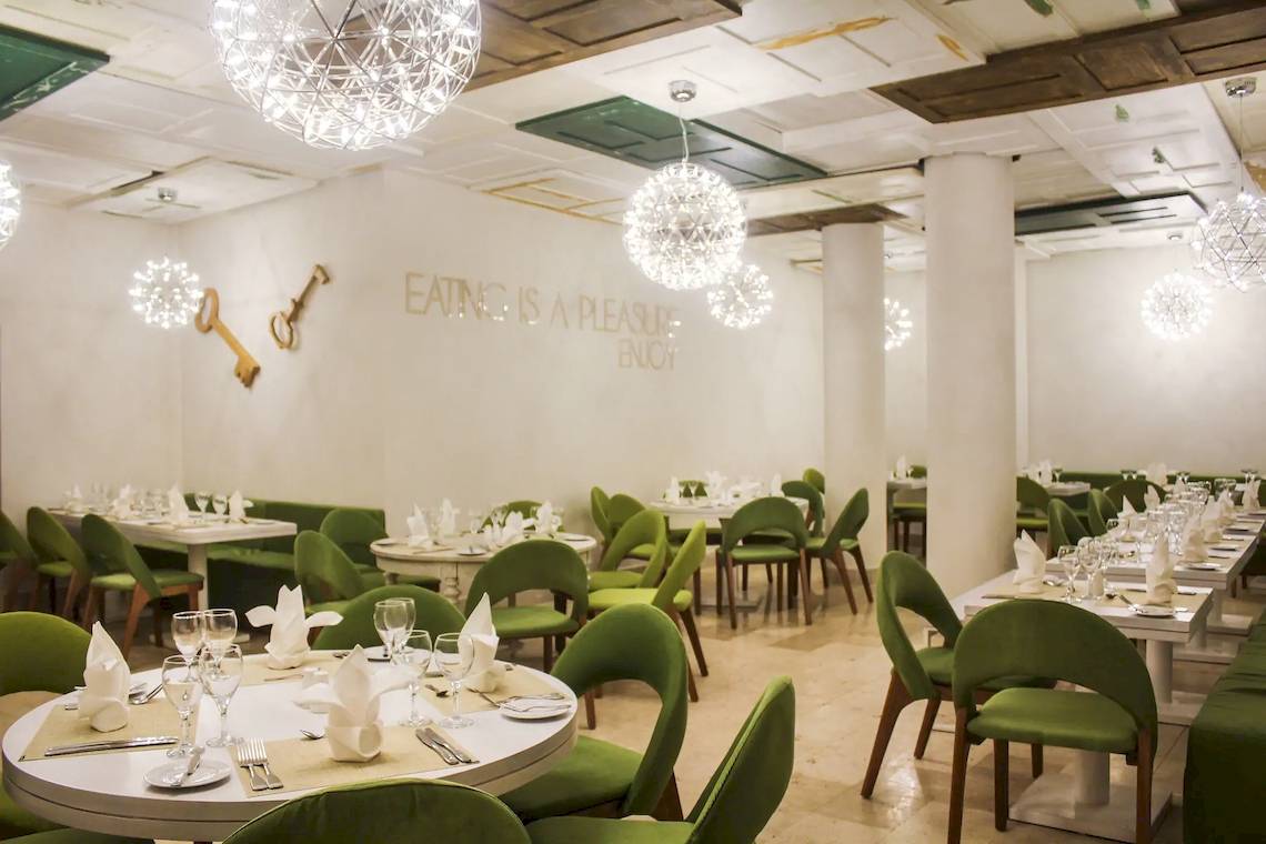 Speisesaal des Viva Tangerine by Wyndham Hotels mit grünen Stühlen und Tischdecken.
