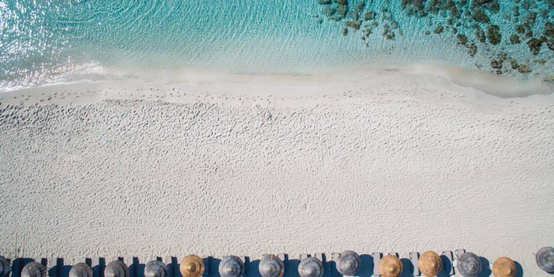 Luftaufnahme des weißen Sandstrands und der Reihe von Sonnenschirmen am Nissi Beach Resort.