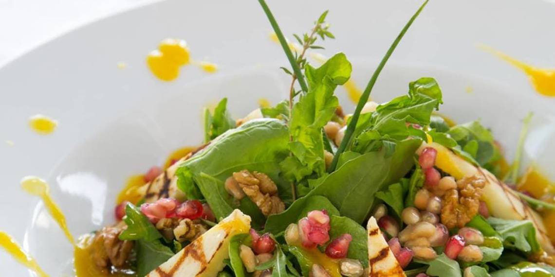 Ein Salat mit Rucola, Granatapfel, Walnüssen und Dressing.