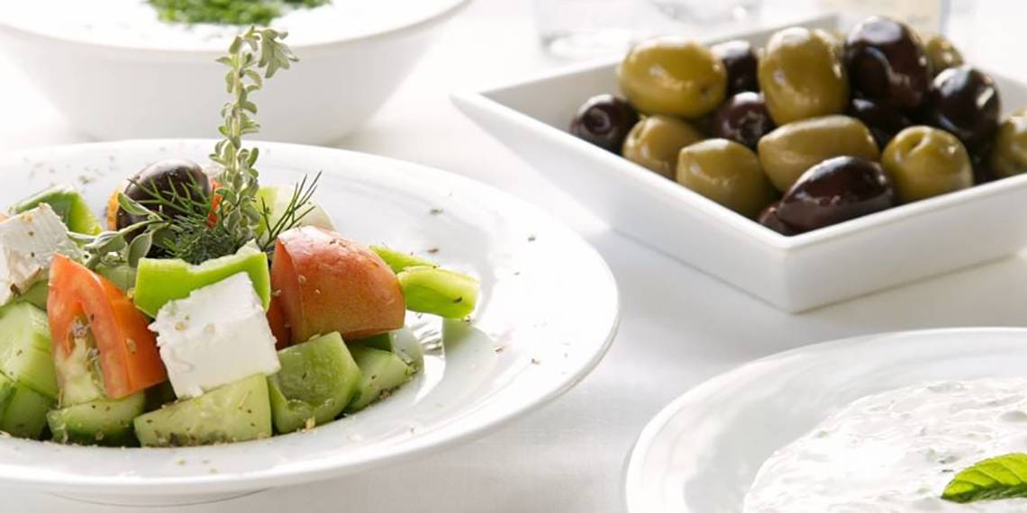 Ein Tisch des Nissi Beach Resorts mit einem gemischten Salat, Oliven und Tzatziki