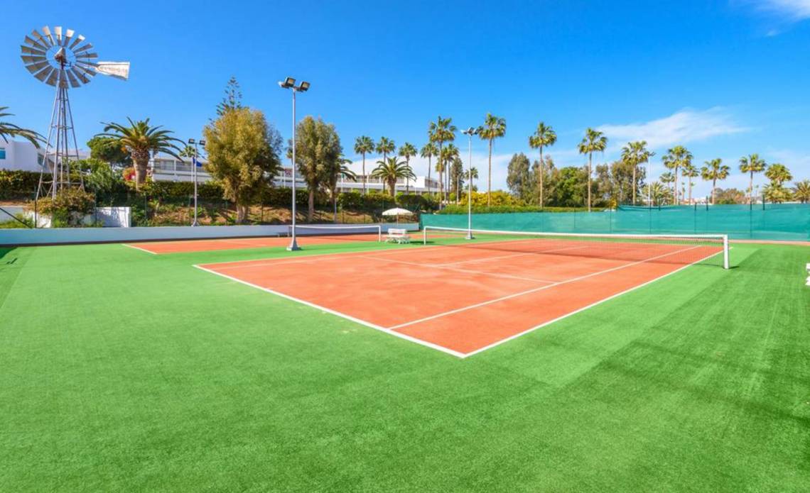 Tennisplatz im Nissi Beach Resort mit grünem Kunstrasen und roten Spielfeldern.