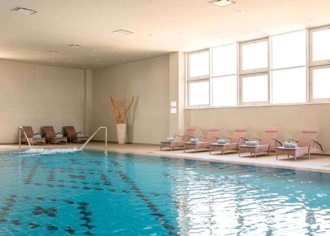 Poolbereich im Nissi Beach Resort mit Liegestühlen und Sonnenliegen.