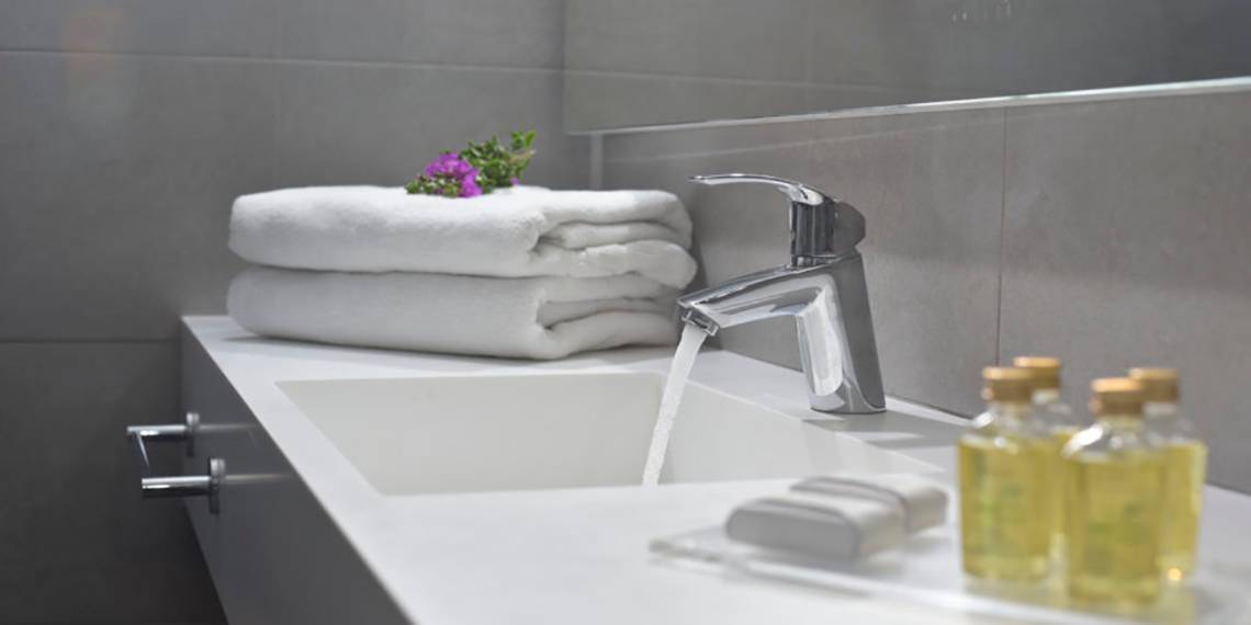 Badezimmer im Nissi Beach Resort mit fließendem Wasser, Handtüchern und Pflegeprodukten.