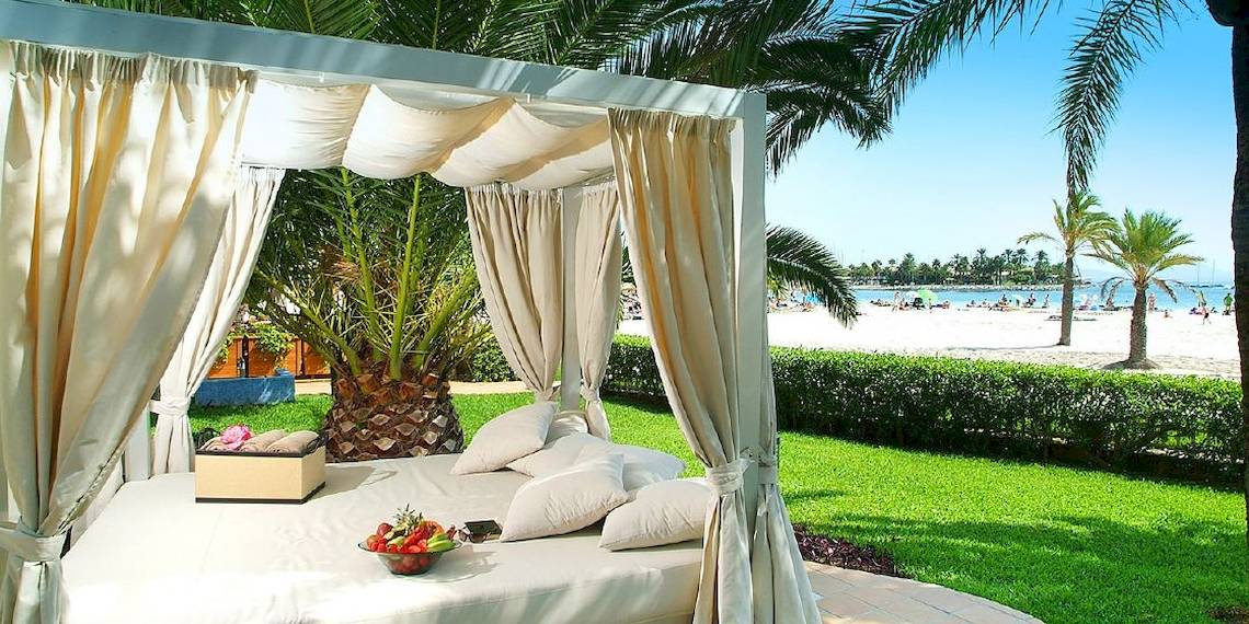 Viva Golf Adults Only Hotel Strandbett mit Baldachin auf dem Rasen neben einem Palmenbaum.